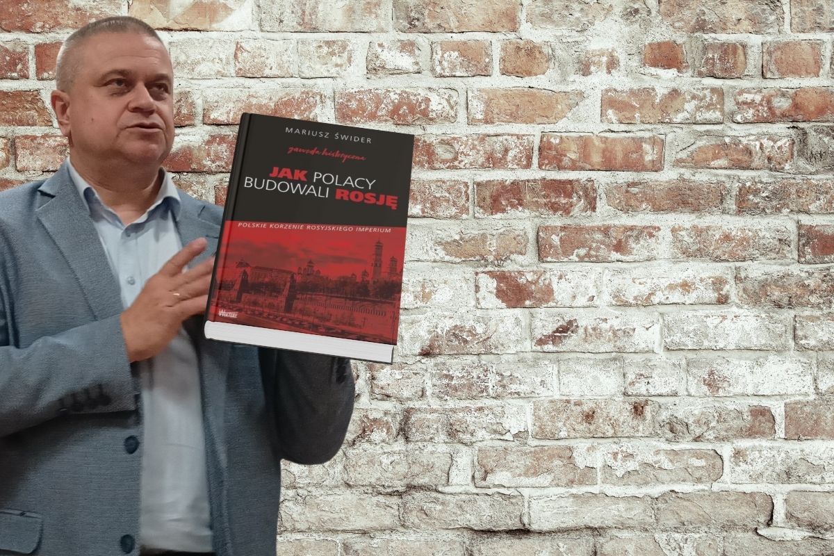 Mężczyzna z książką. W tle ceglany mur.