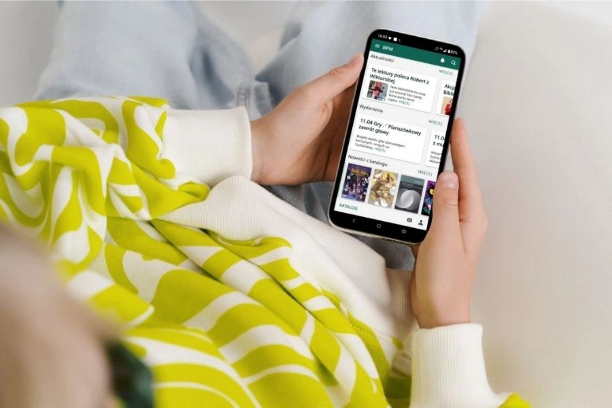 ręce trzymające smartfon z otwartą aplikacją biblioteczną