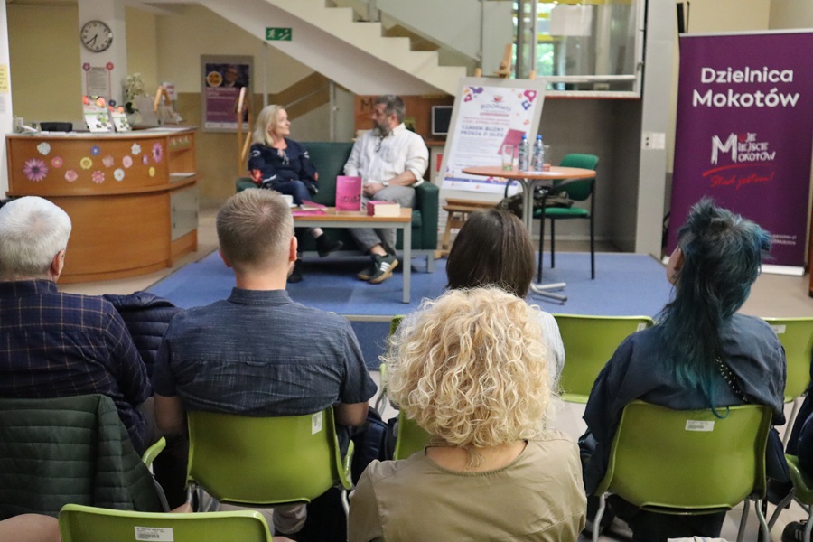 wieczór autorski w bibliotece, ludzie tyłem, na scenie poetka i poeta